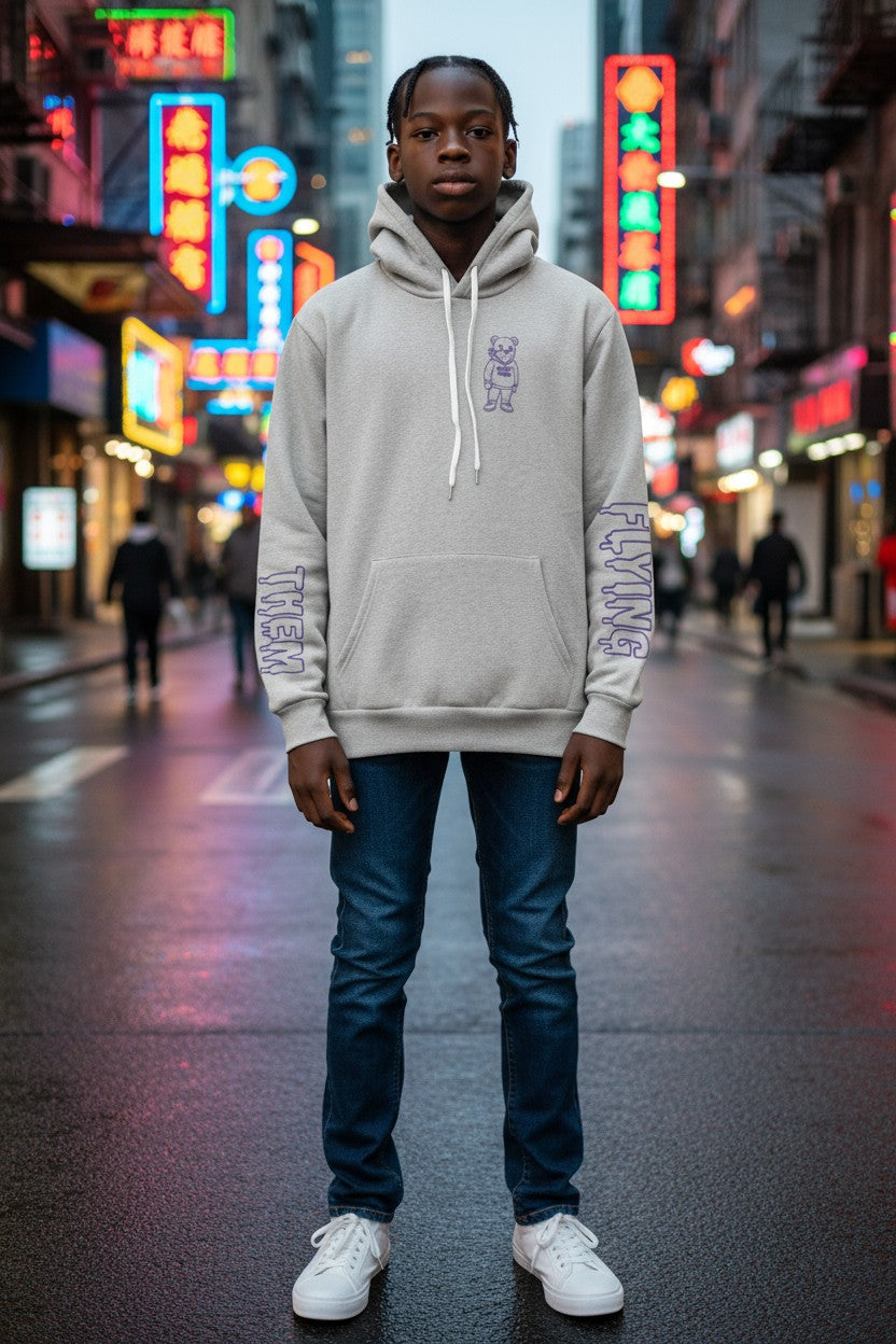 Person wearing a light gray FT hoodie with text on a city street at night.